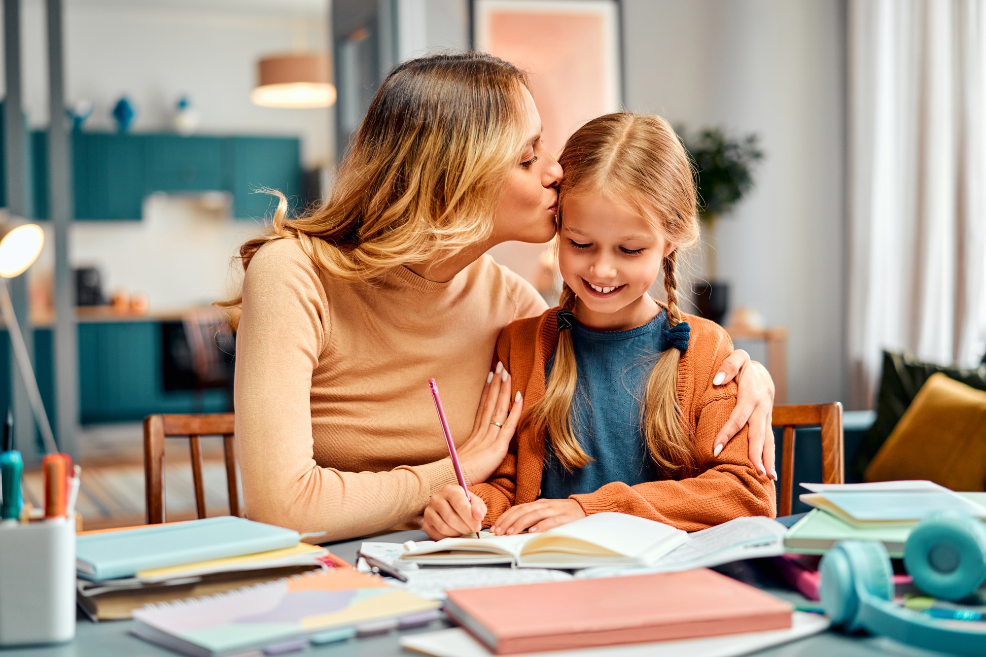 Concept of motherhood. Smiling girl receiving dose of motivation from mum kissing her in forehead